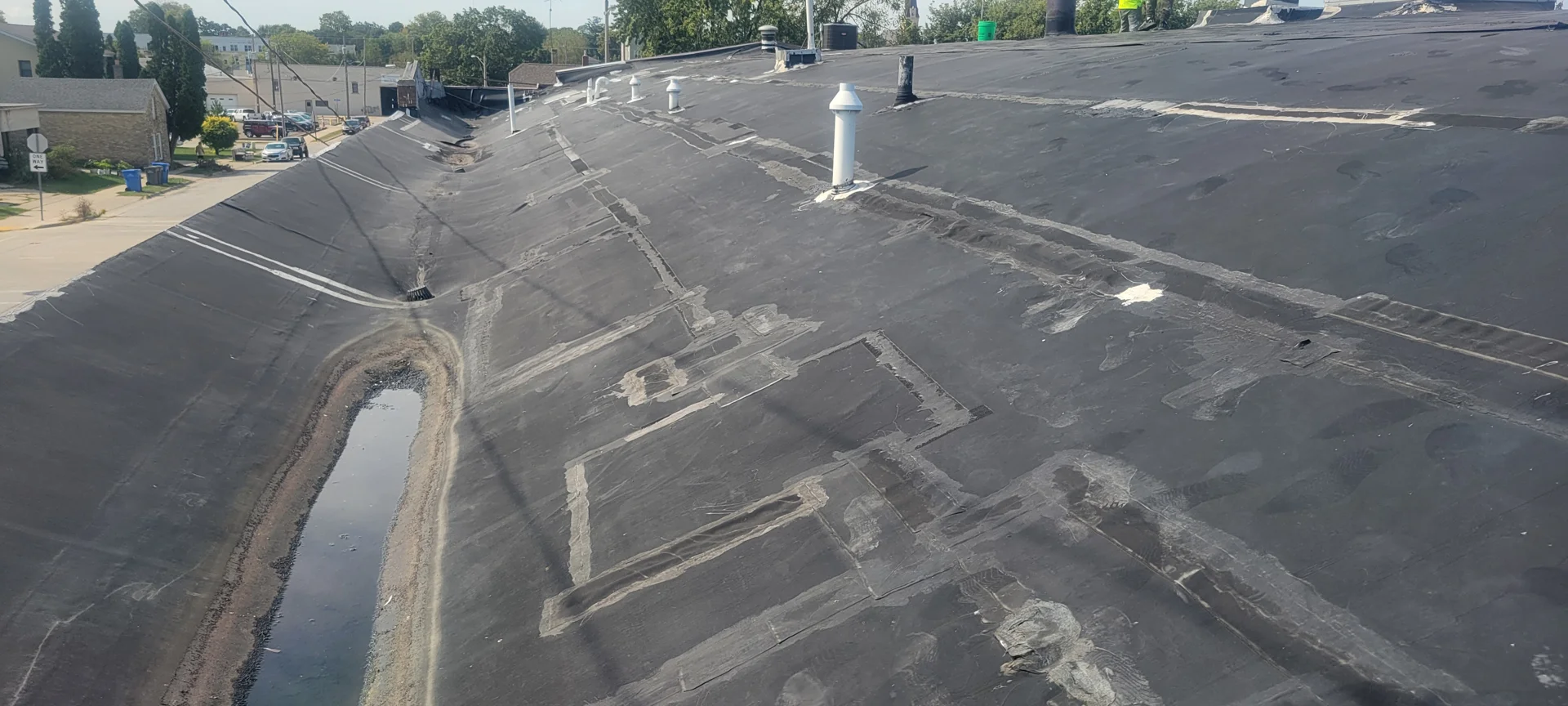 emergency roof seal on commercial flat roof during storm with active leaks and water damage